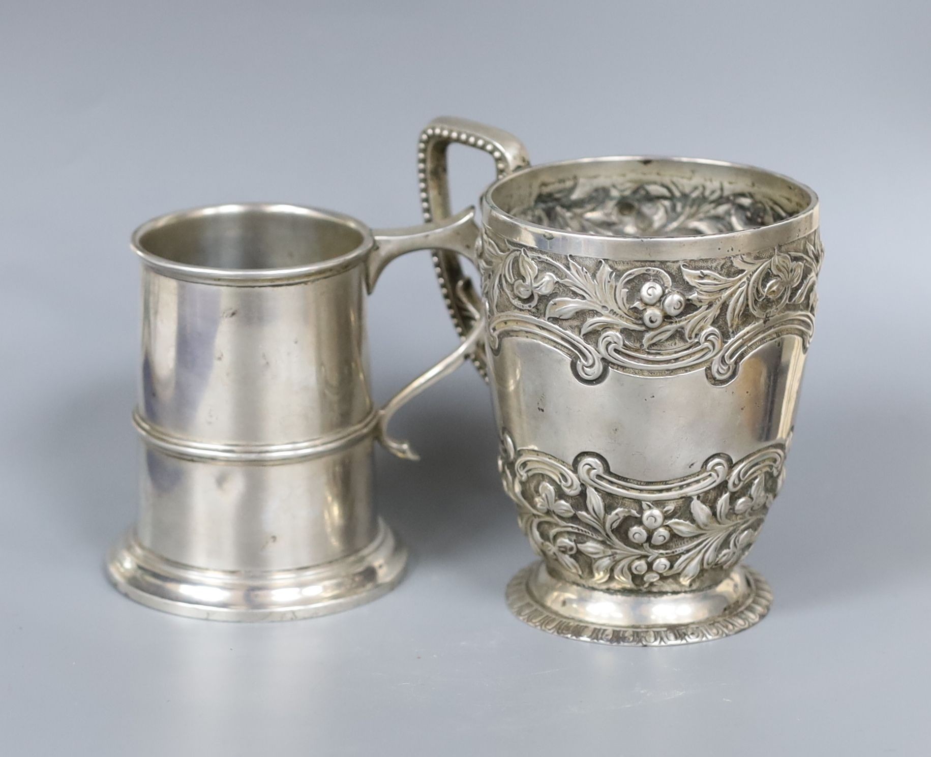 A late Victorian embossed silver christening mug, London, 1895, 10.5cm and a similar later silver mug, 10.5oz.